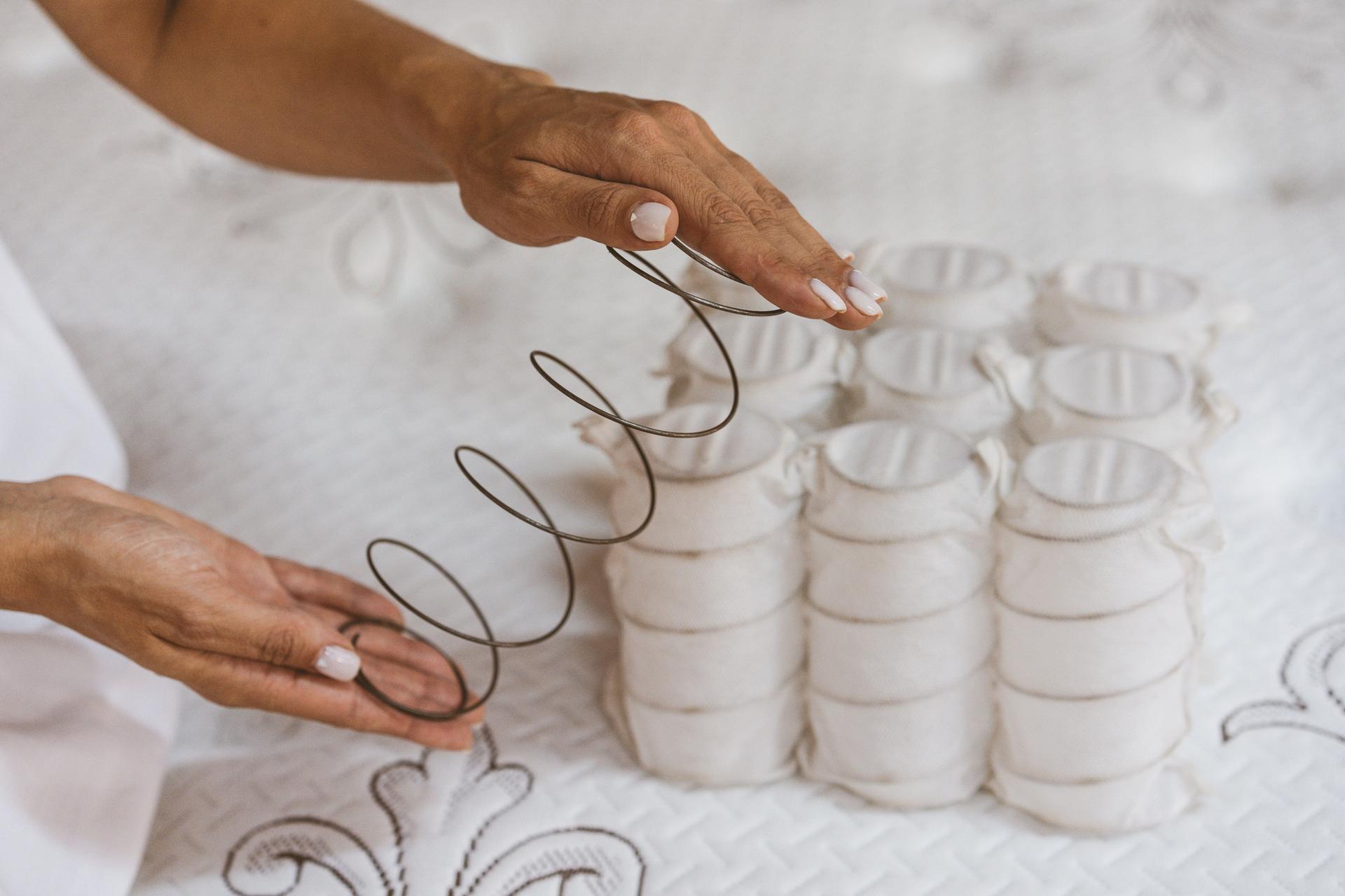 Mattress spring in the hands of a woman. Pocket independent spring. The concept of filling a mattress.
