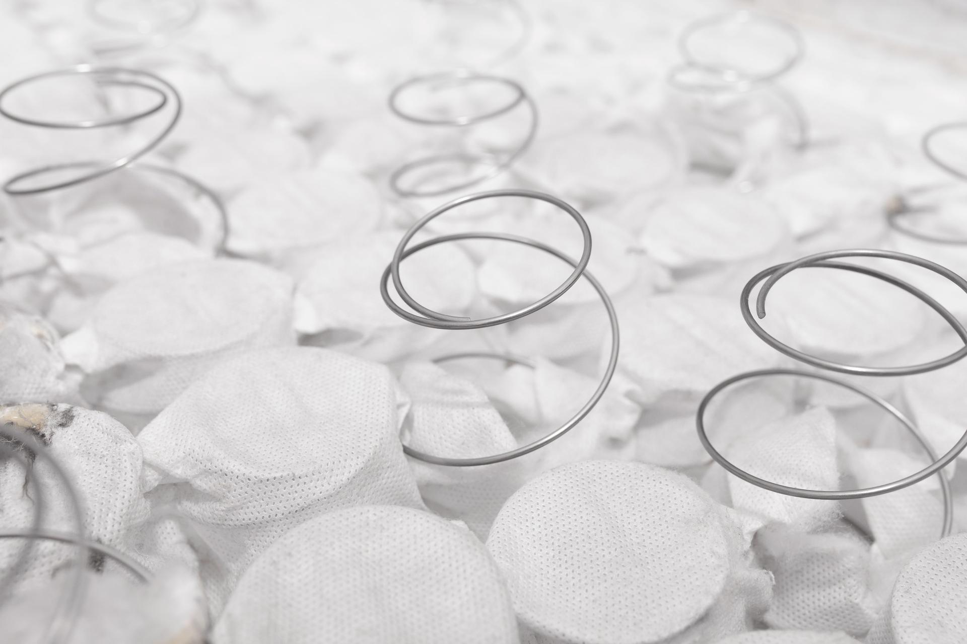 Pocket independent spring sewn in white span-bond mattress base with metal springs poking out