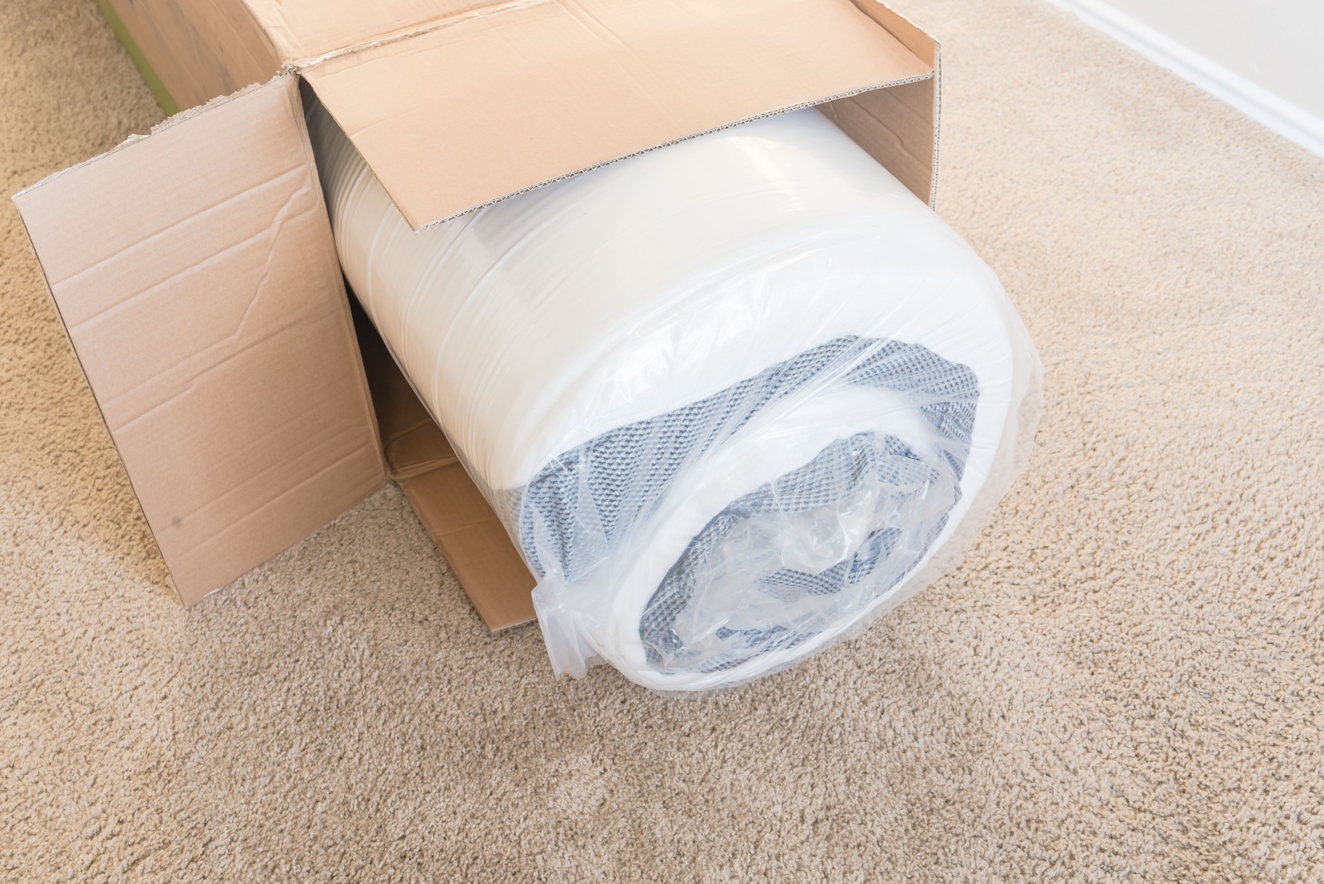 Close-up top view roll-packed spring mattresses unbox on carpet floor background